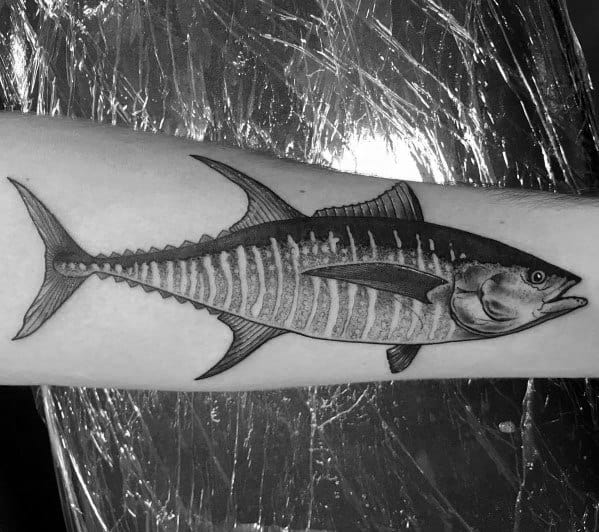 Realistic black and grey tuna fish tattoo on a man's forearm, featuring fine line details, intricate shading, and a lifelike anatomical design.