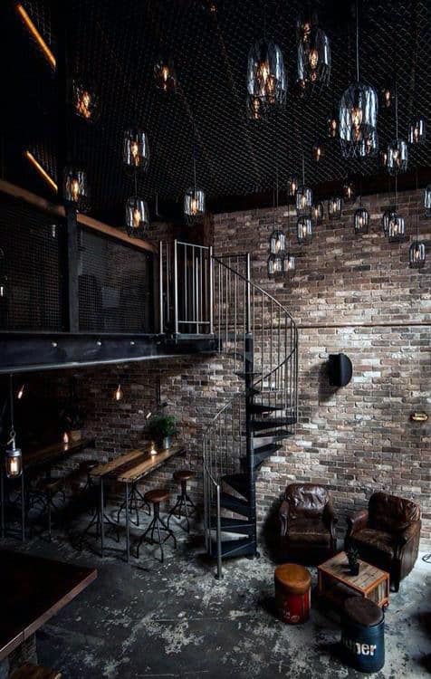Garage-style cafe with spiral staircase, brick walls, hanging lights, and cozy seating