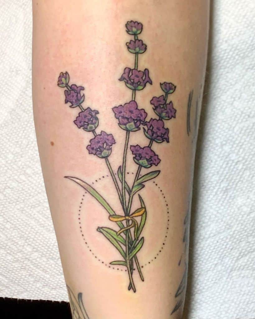 A vibrant lavender tattoo featuring a bouquet of purple flowers tied with a yellow ribbon, surrounded by a dotted circle.