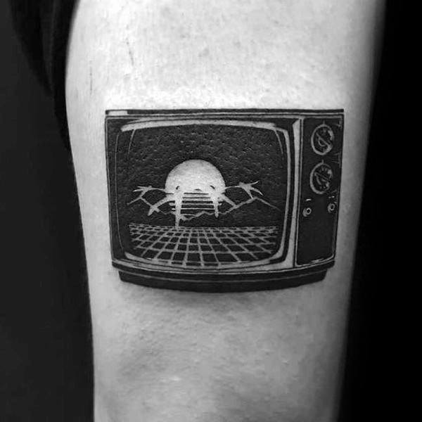 Black and grey tattoo of a vintage TV displaying a retro-futuristic scene with a grid, a rising sun, and birds in flight, blending nostalgia with a sci-fi aesthetic.
