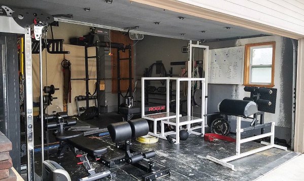 Two-car garage gym with weight benches, cable machine, power rack, and functional training setup.
