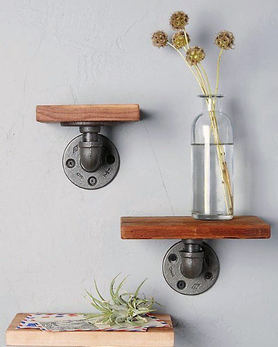 Wall-mounted industrial pipe shelves with a vase and plant on a gray background