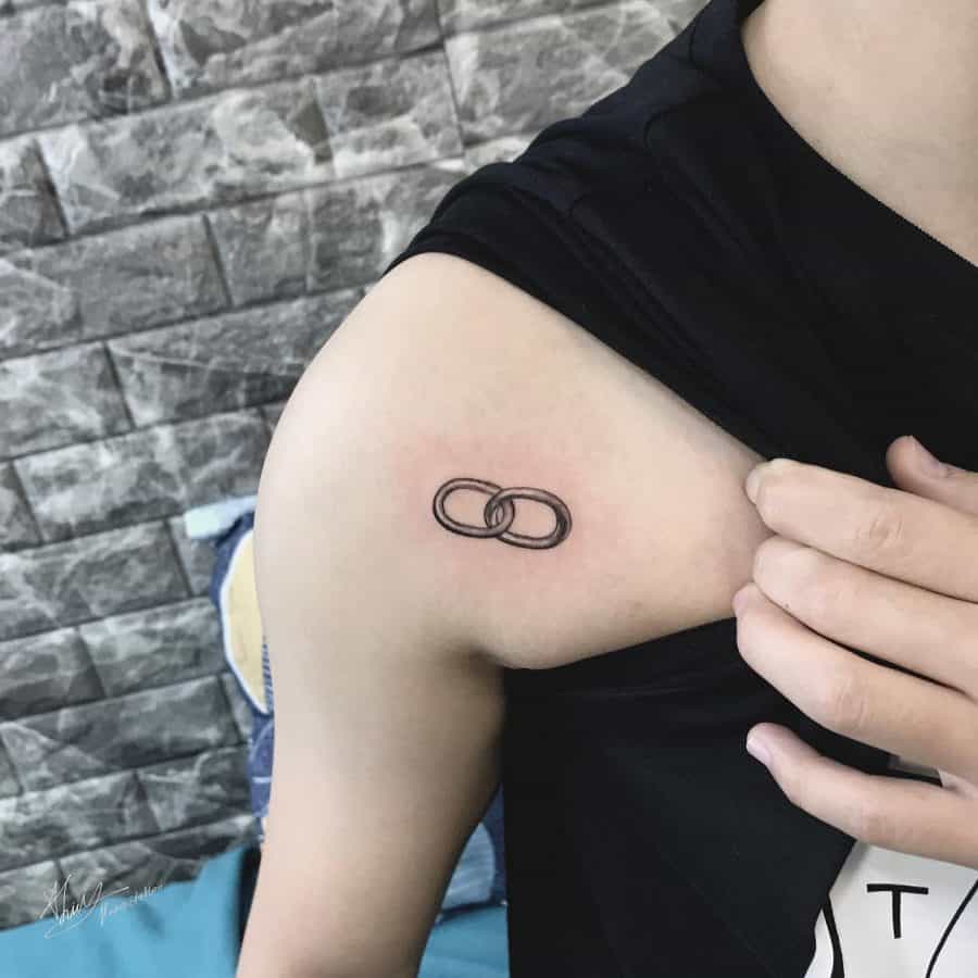 A simple yet meaningful tattoo of two interlocking rings, symbolizing unity and connection.