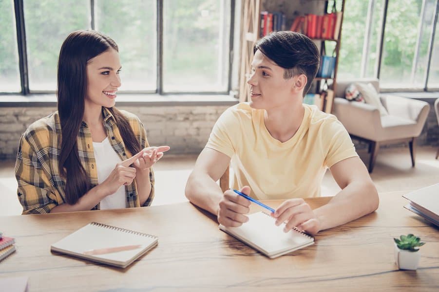 two people students talking writing in notebook