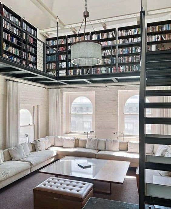 Spacious library with a mezzanine, cozy sofas, large windows, and a modern chandelier