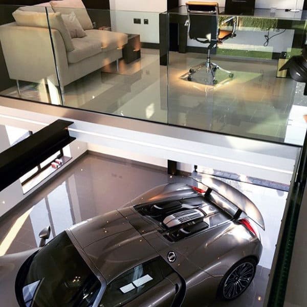 A modern two-story garage with a sleek office and lounge overlooking a luxury car.