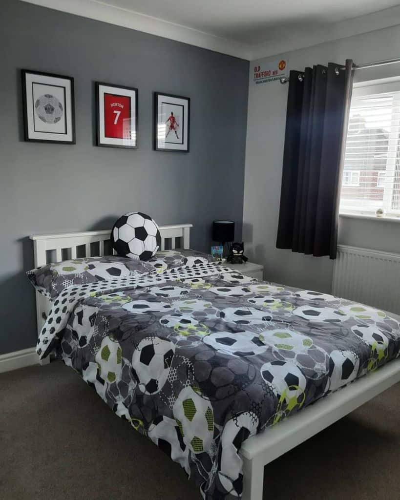 Soccer-themed bedroom with soccer wall art, matching bedspread, and gray curtains.