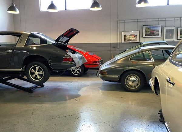 A vintage-inspired garage showcasing classic cars under warm industrial lighting, with one vehicle on a lift for maintenance.