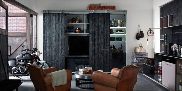 Cozy living space with leather chairs, TV, bookshelves, and a motorcycle in a garage-inspired setting