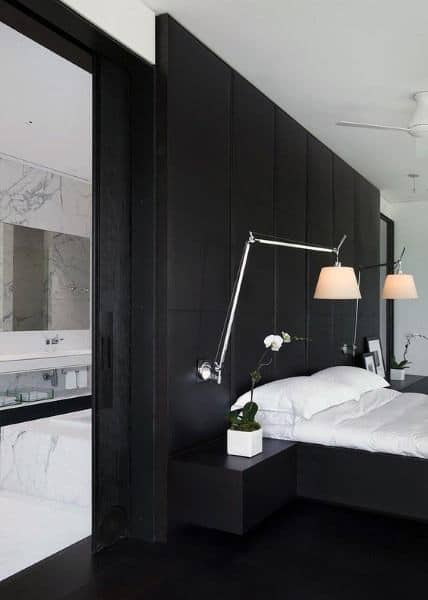 Ultra-luxury black bedroom with sleek black panel wall, modern adjustable wall lamps, and minimalist decor.
