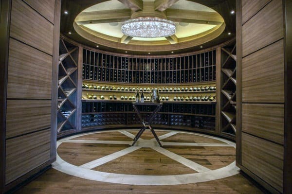 Circular wine cellar with wooden shelves, a chandelier, and a wine-inspired wooden floor with an X pattern