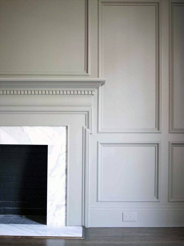 White marble fireplace with a detailed wood mantel and elegant paneled wall design.