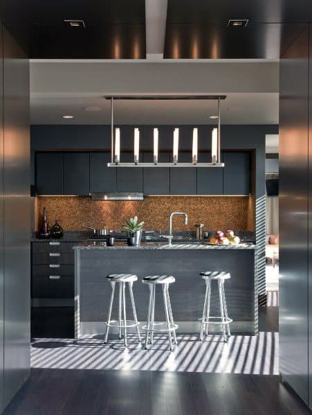 Modern black kitchen with sleek cabinets, a central island, and metal bar stools.
