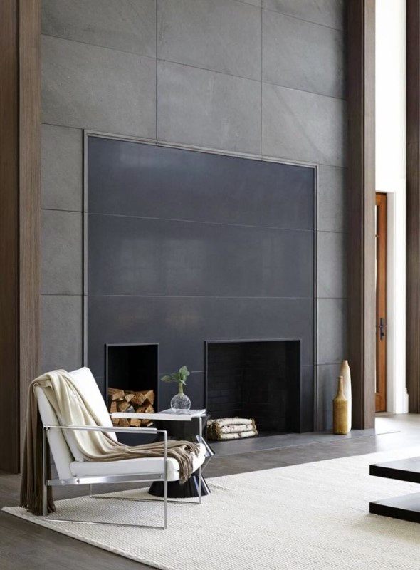 A sleek modern fireplace with a dual firebox design, contrasting black and gray panels, and built-in wood storage for a contemporary and functional aesthetic.