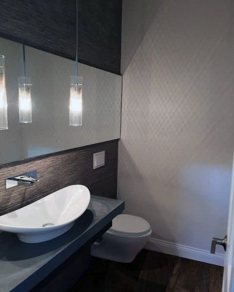 Modern half bath with a vessel sink, wall-mounted faucet, pendant lights, and a compact white toilet