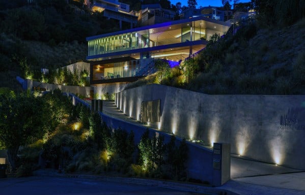 Ultra-modern driveway with dramatic lighting highlighting the sloped path, casting soft glows along the contemporary architecture and landscaping at night