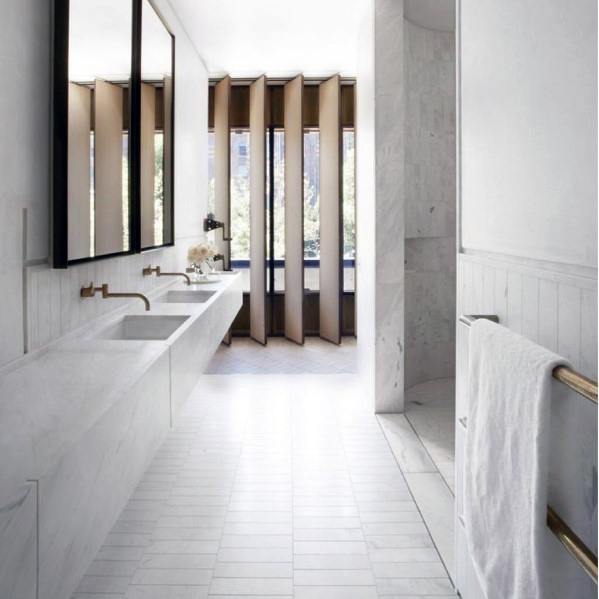 Sleek white bathroom with large mirrors, dual sinks, and vertical window blinds