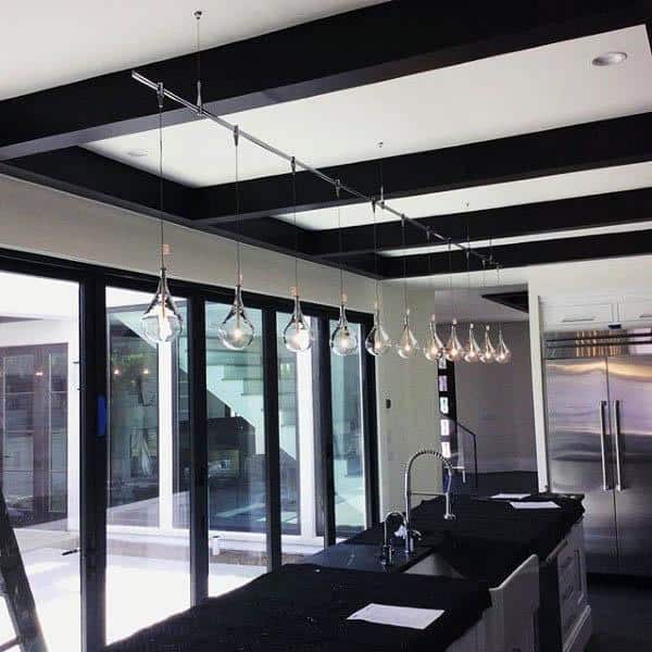 Modern kitchen with sleek pendant lighting and black countertops.