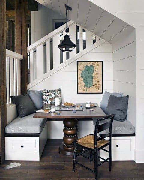 Cozy nook with benches, map wall art, and a black pendant light tucked under a staircase
