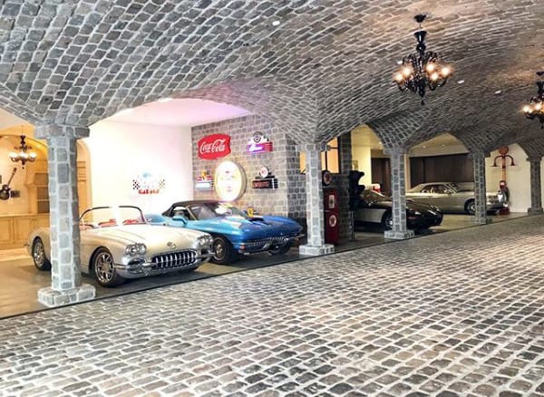 Underground dream garage with cobblestone flooring, arched stone ceilings, and vintage cars for a timeless appeal.
