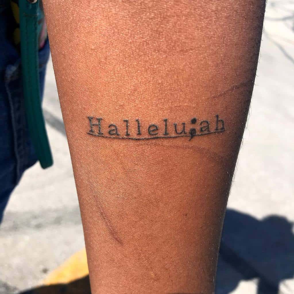 This tattoo features the word "Hallelujah," with a semicolon at the end. The semicolon here could symbolize hope and perseverance, aligning with the positive, celebratory meaning of the word "Hallelujah."