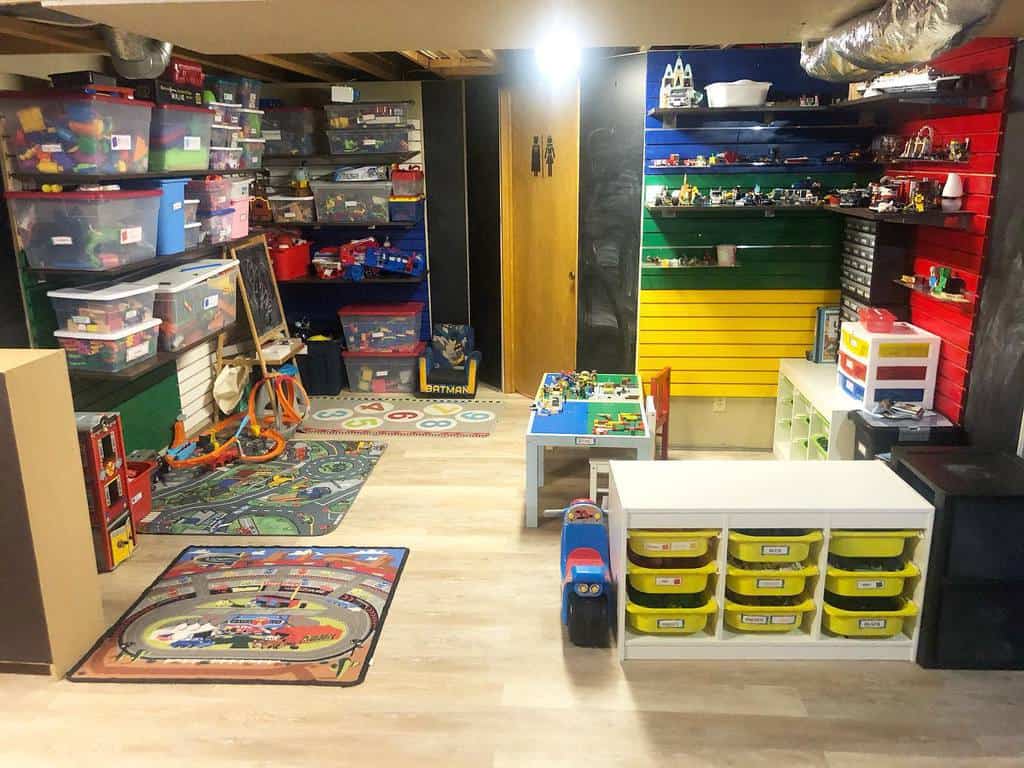Colorful children's playroom with toy storage bins, play mats, and LEGO display wall.