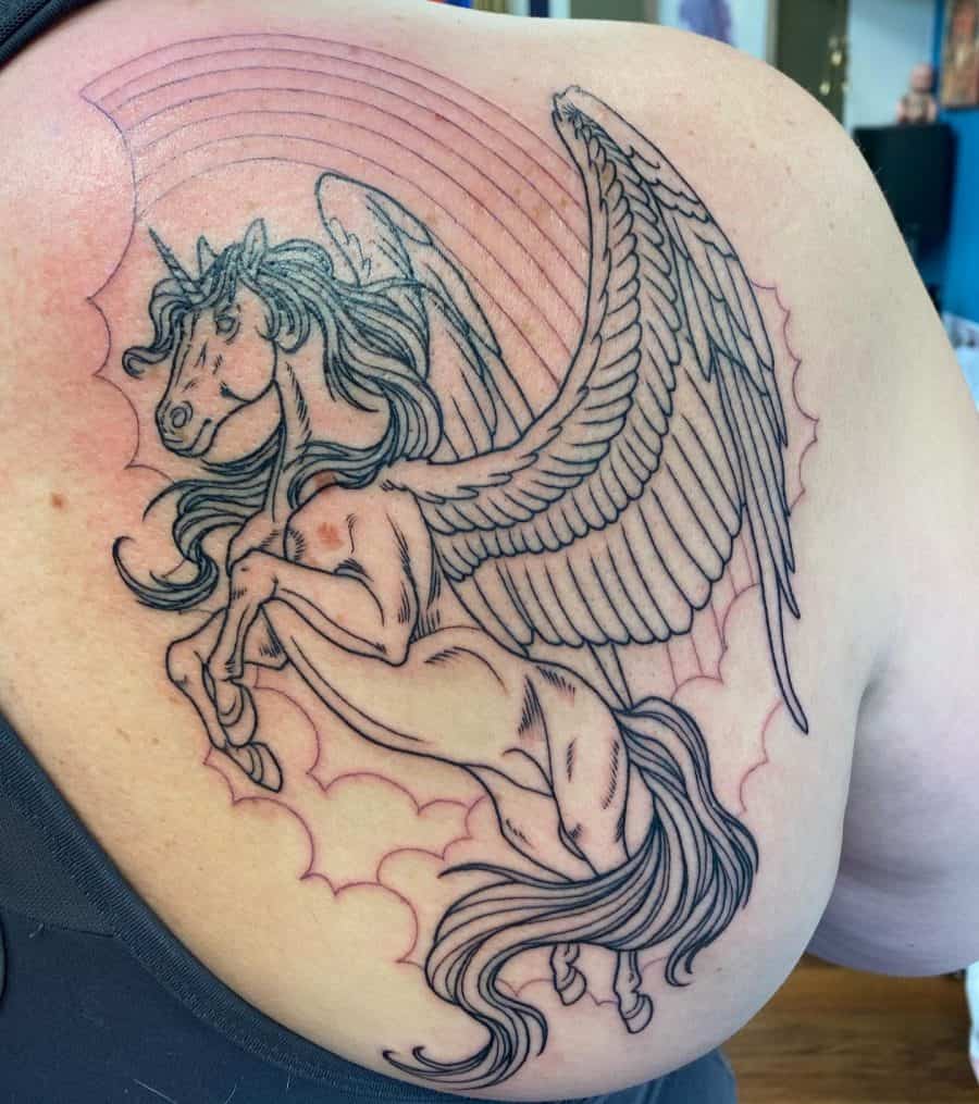 Large black ink tattoo of a majestic winged unicorn rearing up, with flowing hair and detailed feathers, set against a cloud and rainbow background.