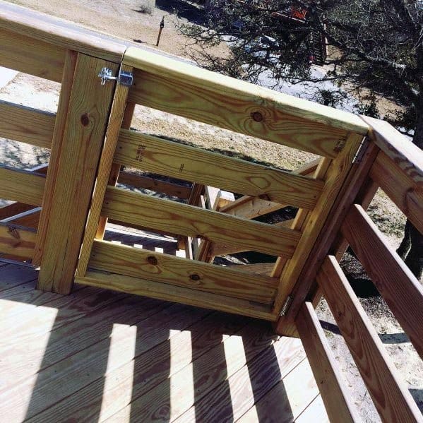 A wooden gate graces the sunlit deck, framed by lush trees