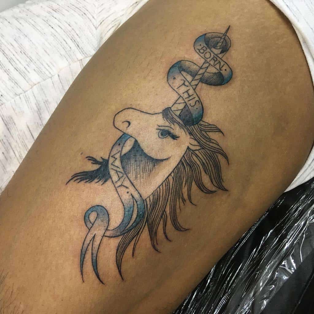 Tattoo of a unicorn with flowing mane, pierced by a sword wrapped with a ribbon saying "Born this way"
