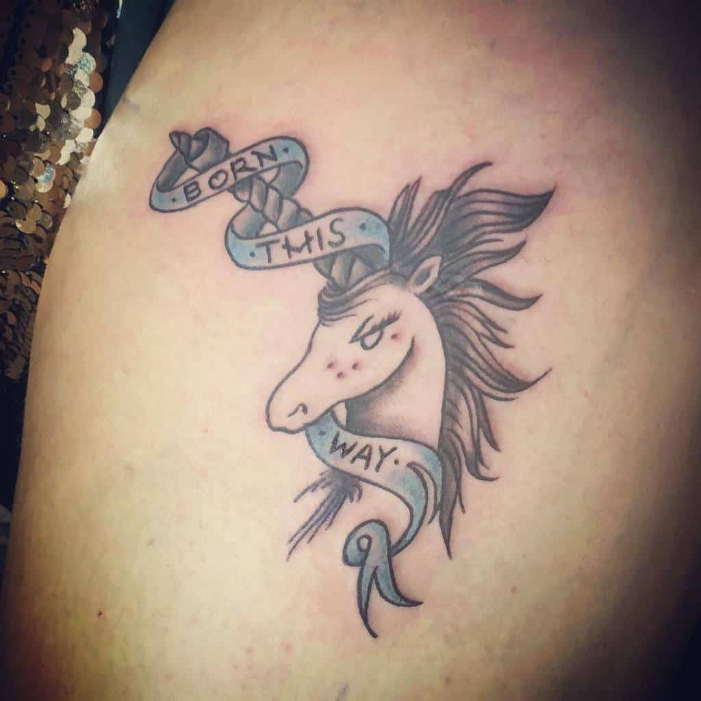 Tattoo of a horse's head with a flowing mane and a ribbon saying "Born This Way"