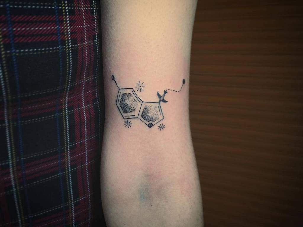 Arm tattoo of a serotonin chemical structure with a small airplane and stars