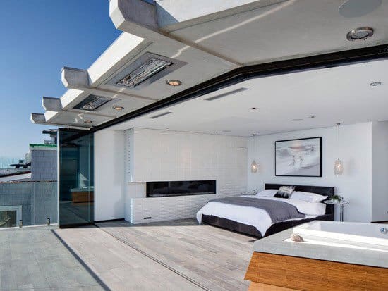 Modern open-concept bedroom with glass walls, white decor, and outdoor view.