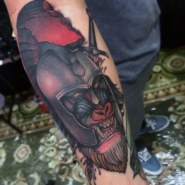Neo-traditional baboon tattoo with bold shading, fierce expression, and a warrior helmet, featuring red battle accents for a powerful arm design.