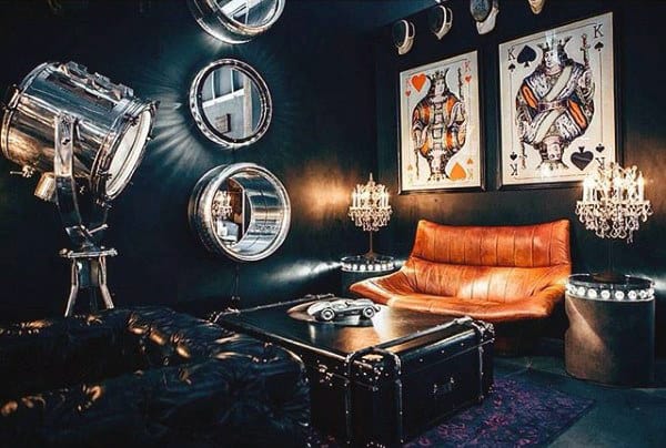 Moody living room with leather sofa, playing card artwork, and industrial-style lighting.