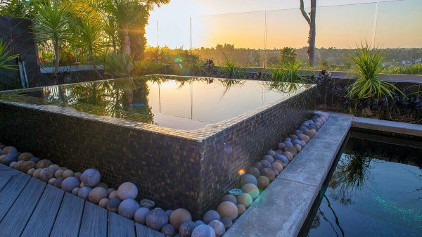 Infinity-style elevated pool surrounded by decorative stones, offering a tranquil sunset view.