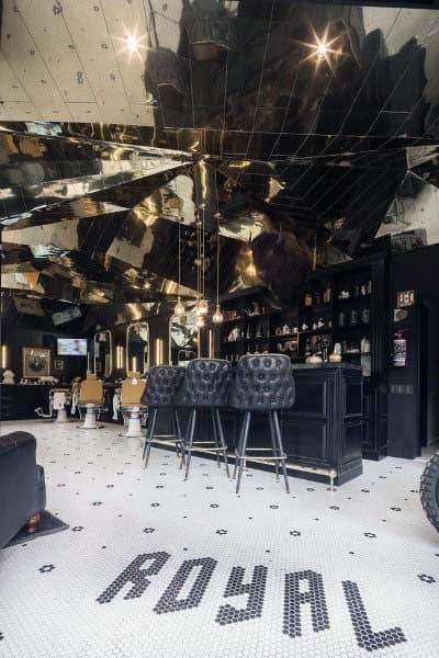 Luxurious barbershop with mirrored ceiling, black bar area, and tiled floor reading "ROYAL".