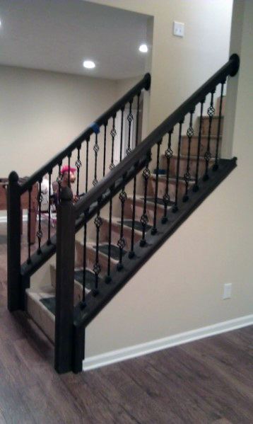 Dark wooden staircase with black metal balusters in a modern home interior.