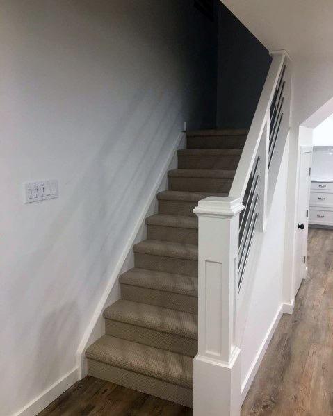 Carpeted staircase with white railing and horizontal metal handrails in a modern home interior.