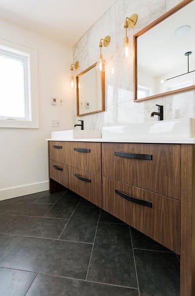 Modern bathroom with wood vanity, black fixtures, and brass overhead mirror sconces.