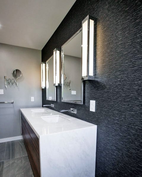 Modern bathroom with dark textured walls, marble vanity, and sleek vertical linear wall sconces.