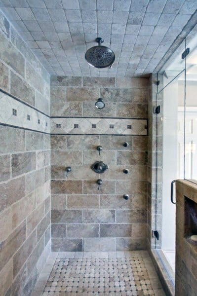 Rustic travertine tile shower with mosaic floor, rainfall showerhead, and multiple body jets.