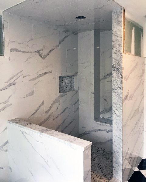 Marble-patterned glossy porcelain tile shower with mosaic niche and partial glass enclosure.