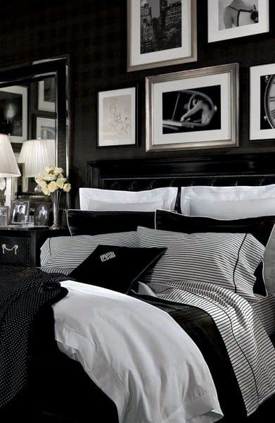 Luxurious black bedroom with striped bedding, framed artwork, and elegant decor accents.