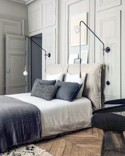 Elegant bedroom with oversized wall-mounted sconces neutral bedding and paneled walls.