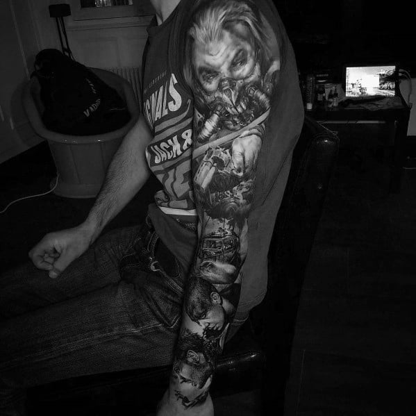 Black and grey full-sleeve tattoo featuring a highly detailed portrait of a villainous character, intense shading, and dramatic cinematic elements.