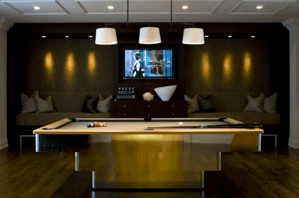Modern billiard room with gold pool table, cozy seating area, and warm ambient lighting.