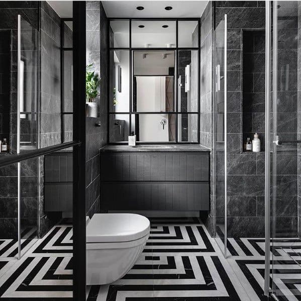 Contemporary black bathroom with geometric flooring, glass partitions, and sleek fixtures.
