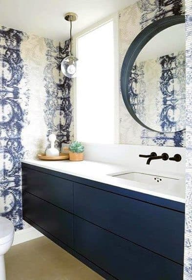 Navy blue vanity with white quartz top and patterned blue wallpaper.