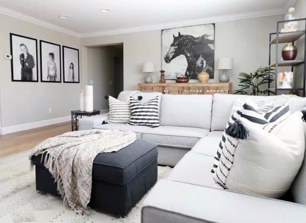 Modern living room with gray sectional sofa, striped pillows, horse artwork, and framed portraits.