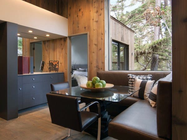 Cozy nook with a wooden table, brown chairs, and a bowl of green apples in a wood-paneled room